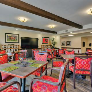A well-decorated dining area with vibrant red chairs, wooden tables, and elegant artwork on the walls.