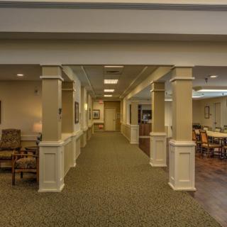 A well-lit interior hallway with columns and a seating area on the left.