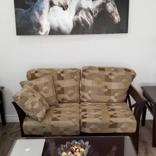 A cozy living room featuring a patterned sofa, coffee table, and horse-themed wall art.