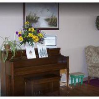 A cozy living room corner featuring a piano adorned with flowers and artwork.