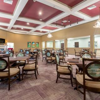 A spacious dining area with multiple empty tables and chairs, adorned with ceiling lights.