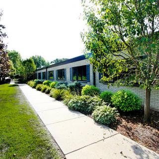 A serene view of a building surrounded by lush greenery and a well-maintained pathway.