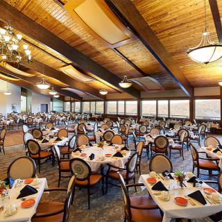 An elegant banquet hall with neatly arranged dining tables and chairs under warm ceiling lights.