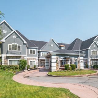 A large, suburban house with a well-maintained lawn and driveway.