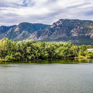A serene view of mountains reflecting in a calm lake surrounded by lush greenery.