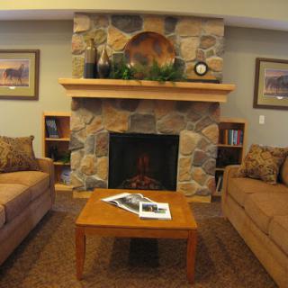 A comfortable living room featuring a stone fireplace, two sofas, and a wooden coffee table.