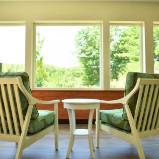 A cozy room with two chairs and a small table overlooking a scenic outdoor view through large windows.