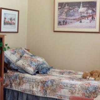 A cozy bedroom with a single bed adorned with decorative pillows and framed artwork on the walls.