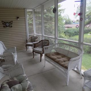 A cozy, screened-in porch with wicker furniture and cushioned seating, offering a relaxing outdoor space.