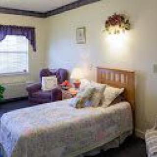 A cozy bedroom with a single bed, armchair, and soft lighting.