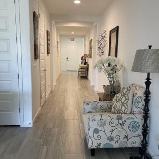 A well-decorated hallway featuring a patterned armchair, floor lamp, and wall art.
