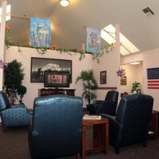 A cozy lounge with comfortable seating, artwork on the walls, and decorative plants.