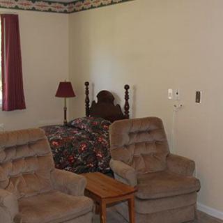 A cozy bedroom with plush chairs and a floral-patterned bedspread.
