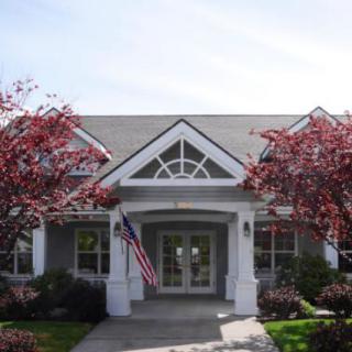 A charming house with a symmetrical front design, flanked by trees and displaying an American flag.