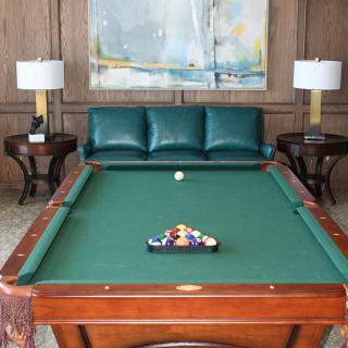 A stylish room featuring a pool table, sofa, and decorative lamps.