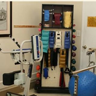 A physical therapy room equipped with various exercise equipment including weights, medicine balls, and rehabilitation machines.