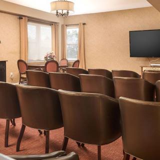 A neatly arranged conference room with rows of chairs facing a television and lectern.