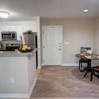 A modern apartment interior featuring an open-concept kitchen and dining area with wood flooring.