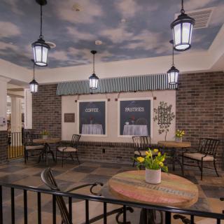 A cozy indoor cafe with brick walls, ceiling murals, and elegant lantern lighting.