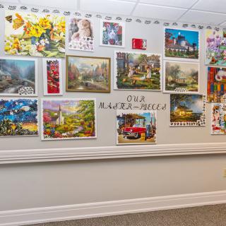 A wall adorned with a colorful collection of paintings, labeled 'Our Masterpieces'.