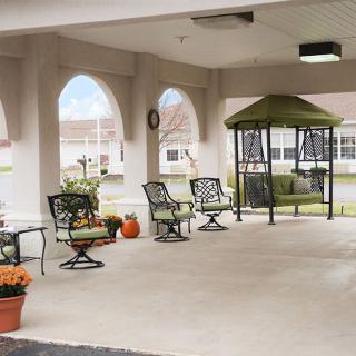 A cozy outdoor patio area with a gazebo, featuring chairs and tables, surrounded by potted plants.