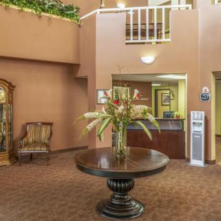 A hotel lobby with a central table adorned with flowers, a reception desk, and seating area.