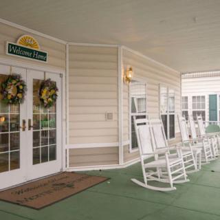 A welcoming porch with rows of white rocking chairs and decorative wreaths on the entrance doors.
