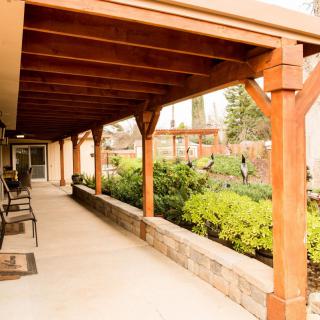 A covered patio with wooden beams overlooks a well-maintained garden area.