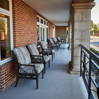 A balcony with rows of cushioned chairs lined up against a brick wall, providing inviting outdoor seating.