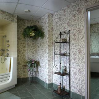 A cozy bathroom corner featuring floral wallpaper and decorative shelving.