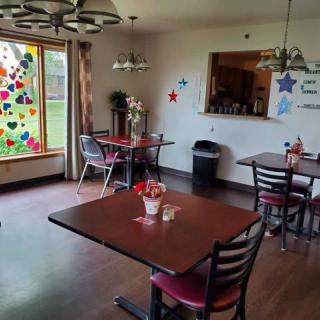 A cozy dining room with decorated windows and several tables set for guests.