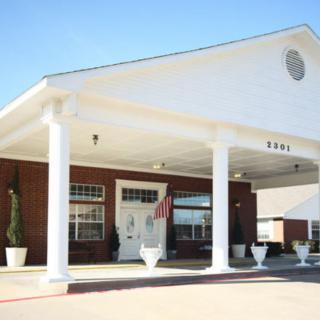 A building entrance with large white columns and a covered driveway.