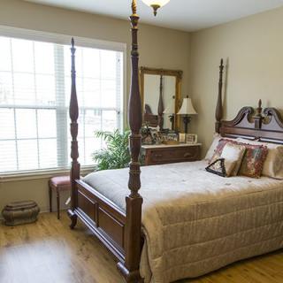 A cozy bedroom with a four-poster bed and warm natural light from a large window.