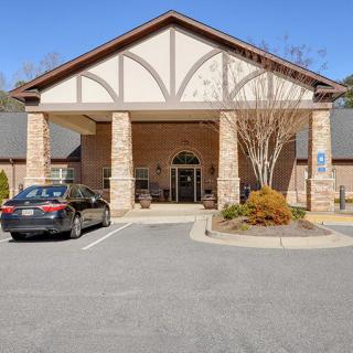 The front entrance of a building with a car parked nearby on a clear day.