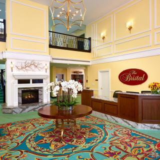 Elegant hotel lobby with a reception desk, chandelier, and cozy fireplace.