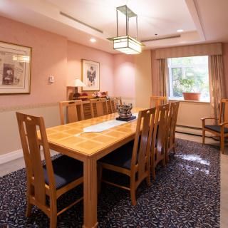 A cozy dining room featuring a wooden table and chairs, with artwork on the walls and natural light coming through the window.