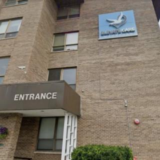 The image shows the entrance of a brick apartment building with signage.