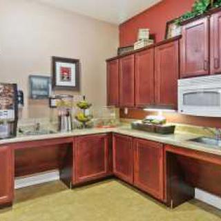 A cozy kitchen with wooden cabinets, a microwave, and a beverage dispenser.