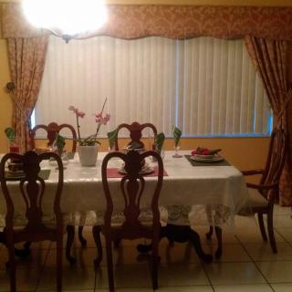 A cozy dining room with a set table and elegant curtains.