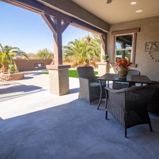 A sunny patio with outdoor furniture and a view of the backyard with palm trees.