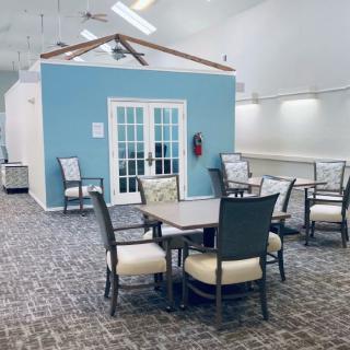 A spacious indoor seating area with tables and chairs, featuring a blue wall with French doors.