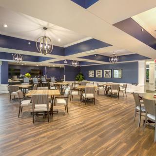 A spacious and modern dining area with blue walls, wooden flooring, and elegant chandeliers.