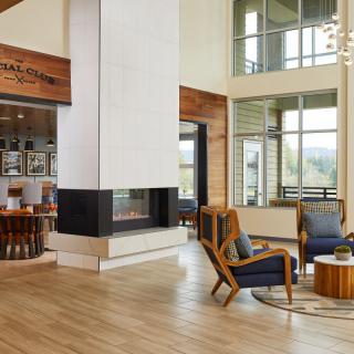 A modern lobby with a central fireplace, wood flooring, and comfortable seating.
