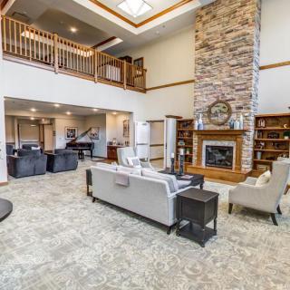 A spacious living room featuring a tall stone fireplace, comfortable seating, and an open loft area.