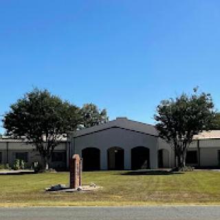 A modern building surrounded by well-maintained landscaping under a clear blue sky.