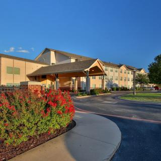 A hotel building with landscaped gardens and a driveway approach.