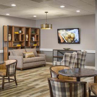 A cozy living room with plaid chairs, a sofa, and a television mounted on the wall.