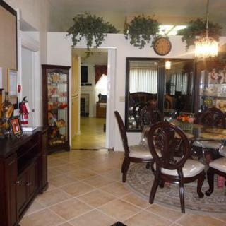 A well-decorated dining room featuring a chandelier, table with chairs, and decorative plants.