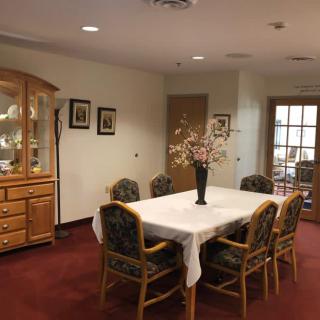 A cozy dining room with a table and chairs, featuring a decorative vase on a white tablecloth.