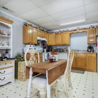 A cozy kitchen with wooden cabinets, a small dining table, and various kitchen appliances.